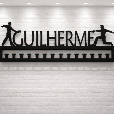 Suporte de metal preto com o nome GUILHERME e figuras humanas, montado numa parede branca de tijolos.