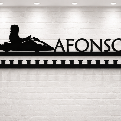 Suporte de medalhas preto com nome AFONSO e silhueta de piloto de kart numa parede branca