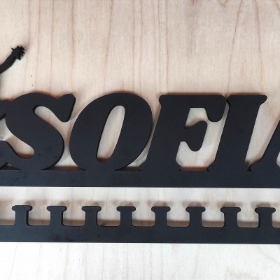 Suporte preto em metal com nome SOFIA e figura de ginasta, com ranhuras para pendurar objetos