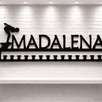 Cabide de ferro preto com nome Madalena e figura de mergulhador montado em parede branca.