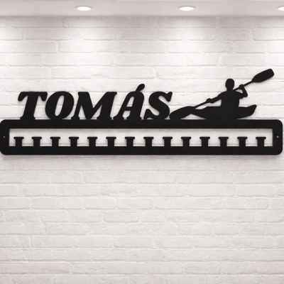 Suporte preto de metal com nome TOMÁS e silhueta de pessoa a remar numa canoa na parede branca