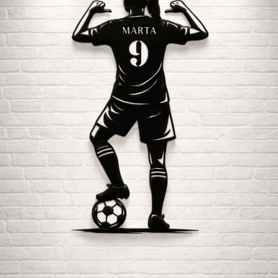 Escultura de parede preta de jogadora de futebol com nome MARTA e número 9 em parede branca de tijolos.