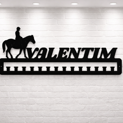 Cabide em metal preto com a palavra VALENTIM e figura de cavalo e cavaleiro numa parede branca