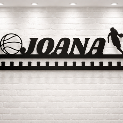 Suporte de medalhas preto com nome JOANA e figuras de basquetebol numa parede branca