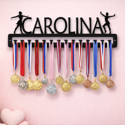 Suporte de metal preto com o nome Carolina e medalhas penduradas numa parede rosa.
