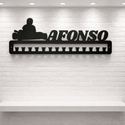 Suporte preto para medalhas com nome AFONSO e piloto de kart, parede tijolo branco.