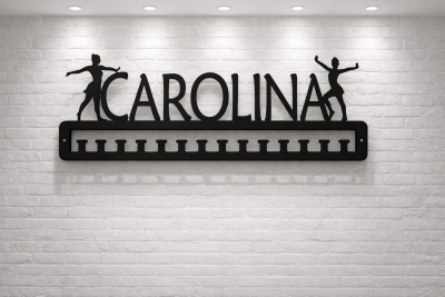 Organizador de medalhas preto com bailarinas e nome Carolina numa parede branca