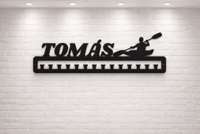 Suporte preto de metal com nome TOMÁS e silhueta de pessoa a remar numa canoa na parede branca