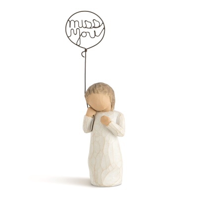 Figura decorativa em madeira com vestido branco segurando balão de arame com frase 'miss you'
