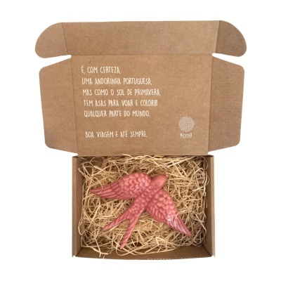 Caixa de cartão castanho com andorinha decorativa rosa em palha de madeira, texto em português na aba interior.