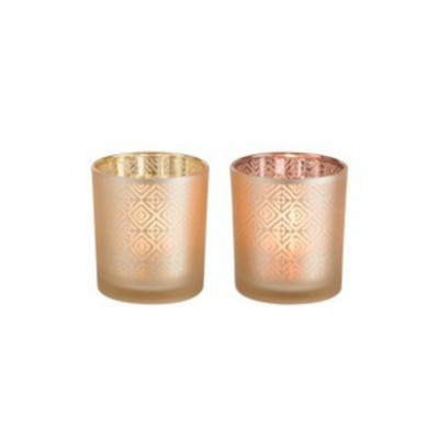 Duas velas decorativas em copos de vidro com padrão geométrico, dourado e rosa