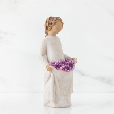 Figura decorativa feminina segurando flores lilases