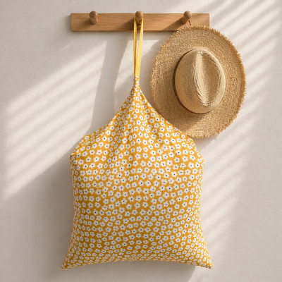 Saco de tecido amarelo com flores brancas e chapéu de palha pendurados no cabide