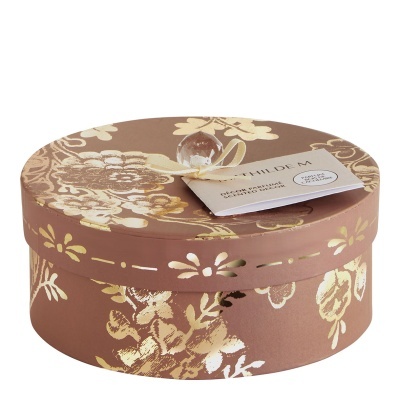 Caixa redonda decorativa castanha com padrão floral dourado e etiqueta de perfume Mathilde M