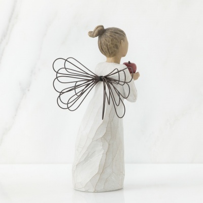 Figura decorativa de anjo com asas de arame pretas e vestido branco segurando um coração vermelho