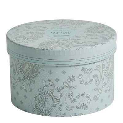 caixa redonda azul claro com padrão floral e tampa com texto