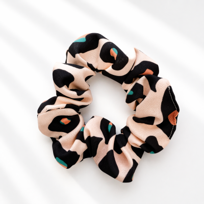 Scrunchie com padrão animal print em tecido bege, preto, verde e laranja