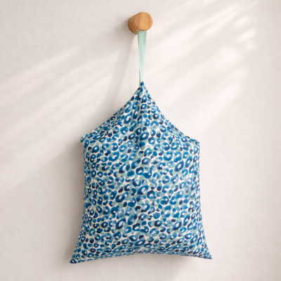 Almofada estampada azul pendurada numa parede branca