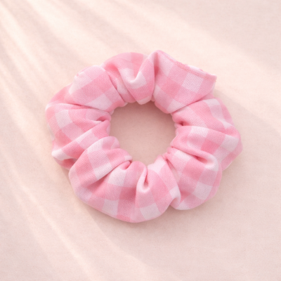 Elástico para cabelo rosa e branco xadrez sobre fundo rosa claro