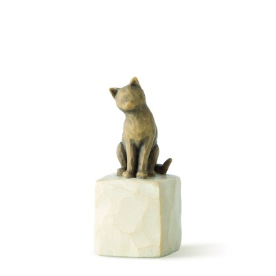 Estatueta de gato castanho sentada num cubo branco de madeira
