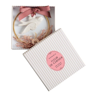 Ornamento decorativo com pássaro branco e flores secas, embalado numa caixa com etiqueta rosa.