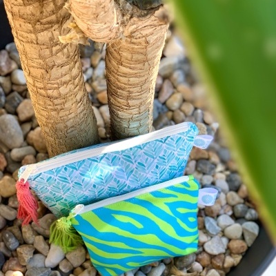 Duas bolsas de tecido coloridas com fechos, entre pedras e troncos de planta