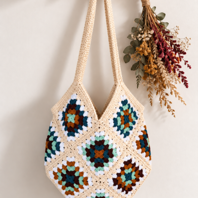 Bolsa de crochet colorida pendurada em suporte de madeira com flores secas ao lado
