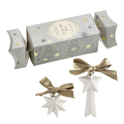 Conjunto de decoração de Natal com estrelas brancas e laços dourados numa caixa cinzenta decorada