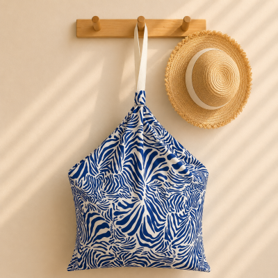 Saco azul e branco pendurado num cabide de madeira com chapéu de palha ao lado