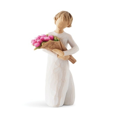 Estatueta de figura feminina ajoelhada com vestido branco segurando flores cor de rosa