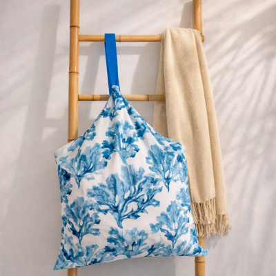 Almofada com padrão azul pendurada em cabide de madeira com manta bege