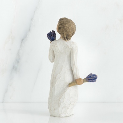 Figura decorativa de mulher com vestido branco segurando flores lilás
