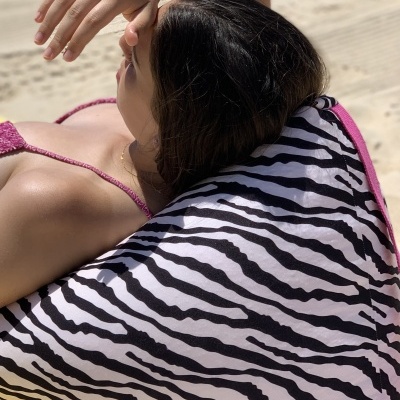 Tecido com padrão zebra preto e branco com bordas cor-de-rosa usado como apoio para costas na praia
