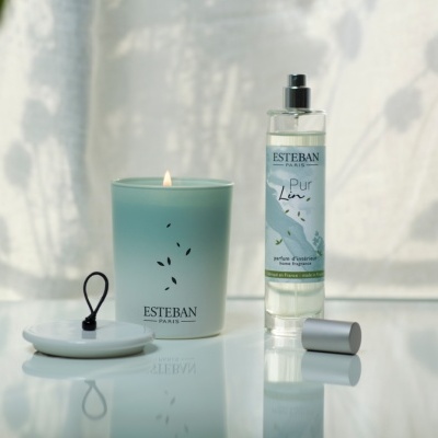 Conjunto de vela aromática e frasco de spray Esteban Paris sobre superfície espelhada