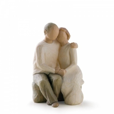 Figura decorativa de casal sentado em tons neutros com textura de madeira