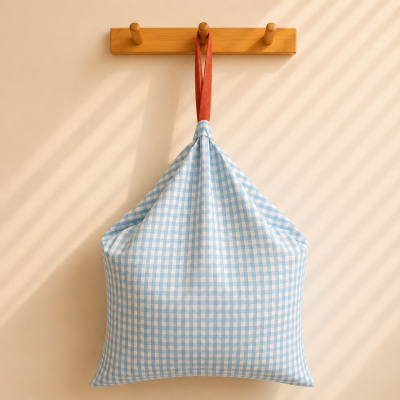 Mochila xadrez azul claro e branco com alça castanha pendurada num cabide de madeira
