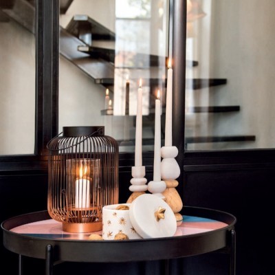 Mesa com lanterna metálica, castiçais e recipiente decorativo com velas acesas