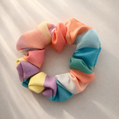 Elástico de cabelo scrunchie com cores pastel variadas sobre superfície clara
