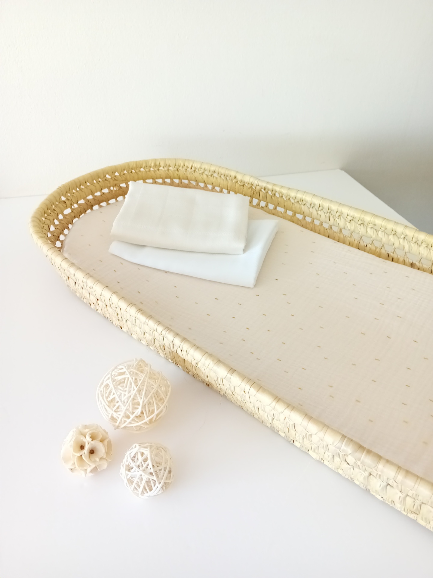 Cesto oval de palha natural com base almofadada bege e bolas decorativas brancas