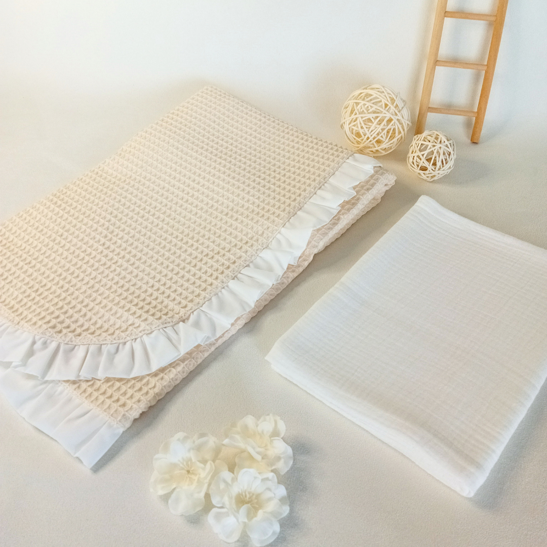 Cobertor bege waffle com folhos brancos e pano branco num cenário com decoração delicada
