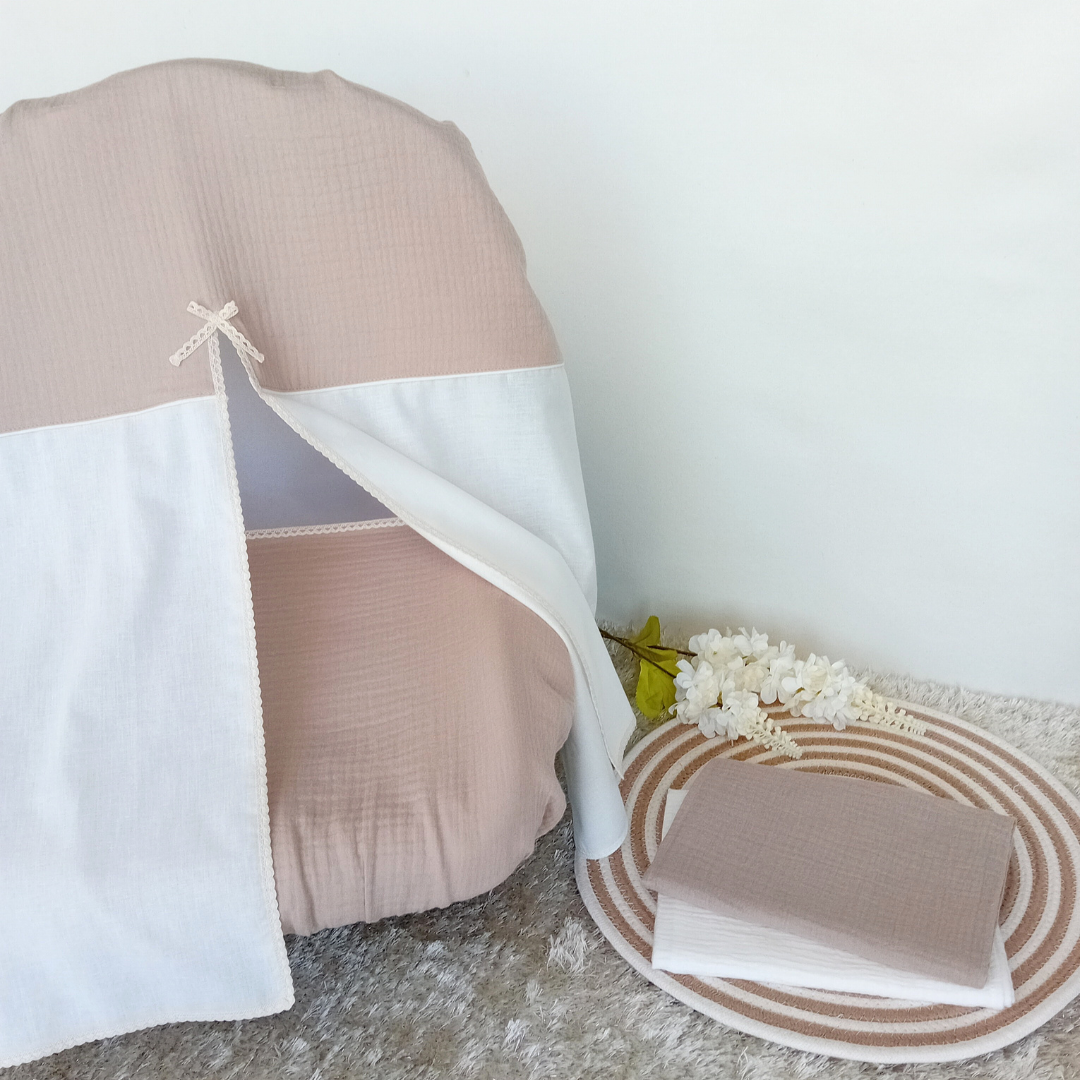 Capa para cadeira rosa e cru com panos de algodão e flores brancas sobre tapete cinza.