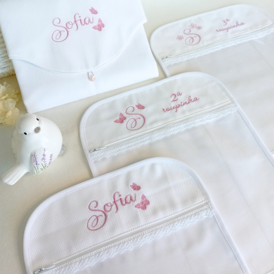 Malas de tecido branco com bordados cor-de-rosa e renda, com fecho, e pássaro de cerâmica ao lado