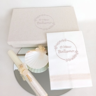 Conjunto de batismo com caixa, toalha bordada e vela decorada sobre um espelho