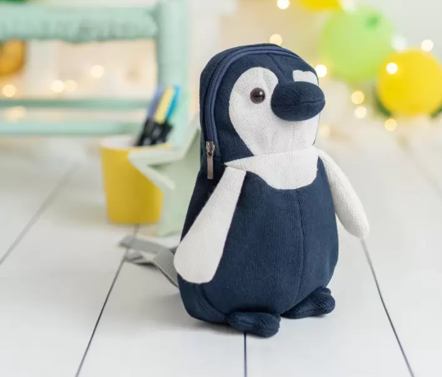 Mochila Pingui Mochila em formato de pinguim azul escuro e branco sobre chão branco