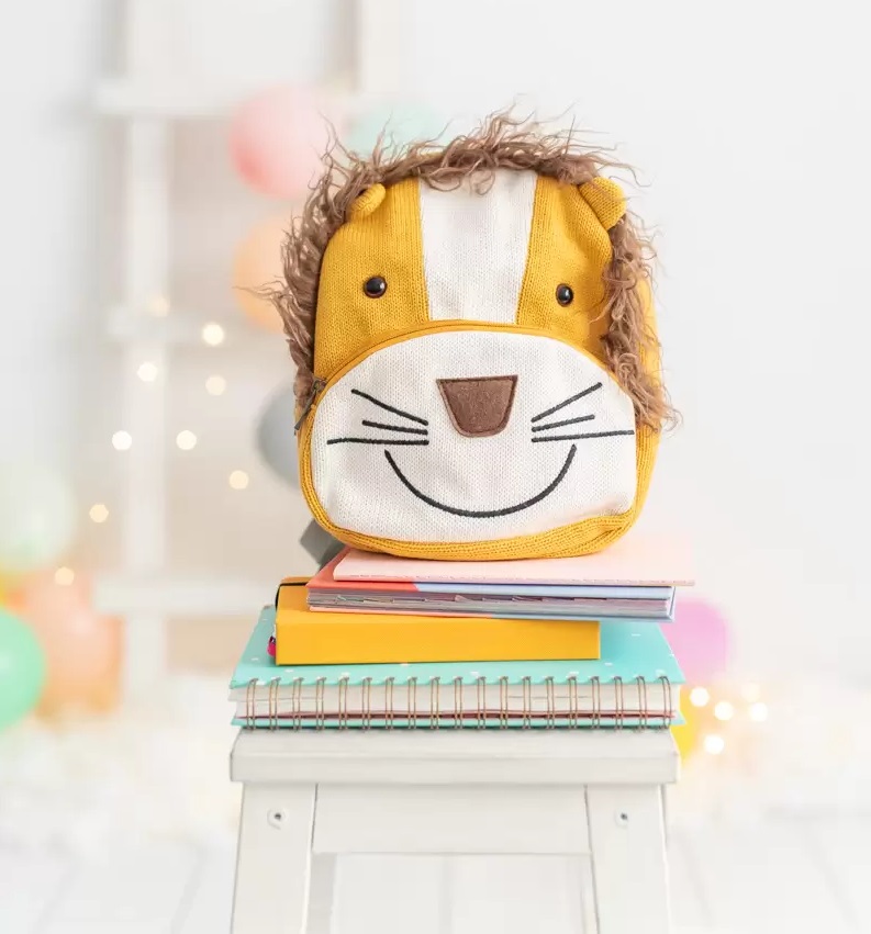 Mochila Simba Mochila infantil com padrão de leão sobre livros e cadernos num banco branco