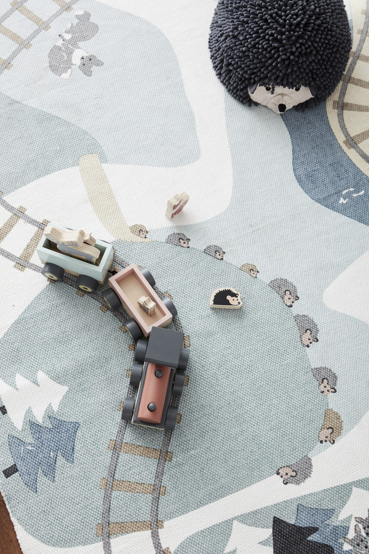 Tapete infantil com padrão de comboio e animais, com comboio de madeira e boneco de ouriço felpudo