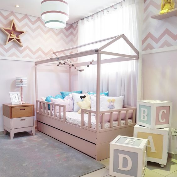 CAMA CABANINHA Quarto infantil com cama-casa rosa, almofadas coloridas, mesa de cabeceira e cubos decorativos com letras