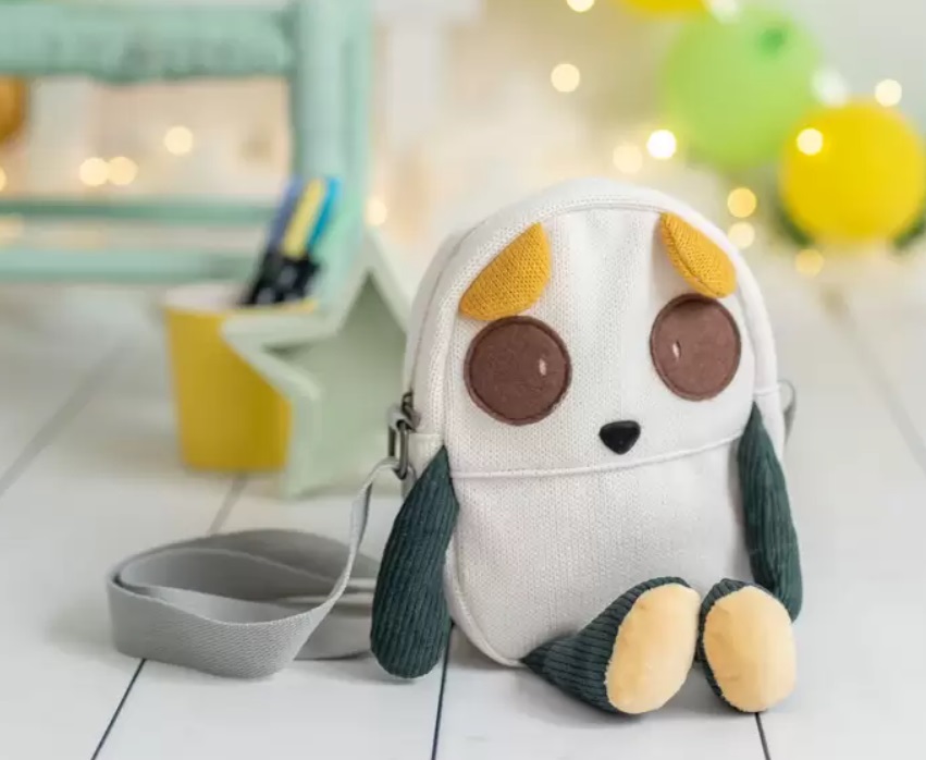 Mala Cuki Mala pequena com forma de animal em tecido branco e detalhes castanhos e amarelos