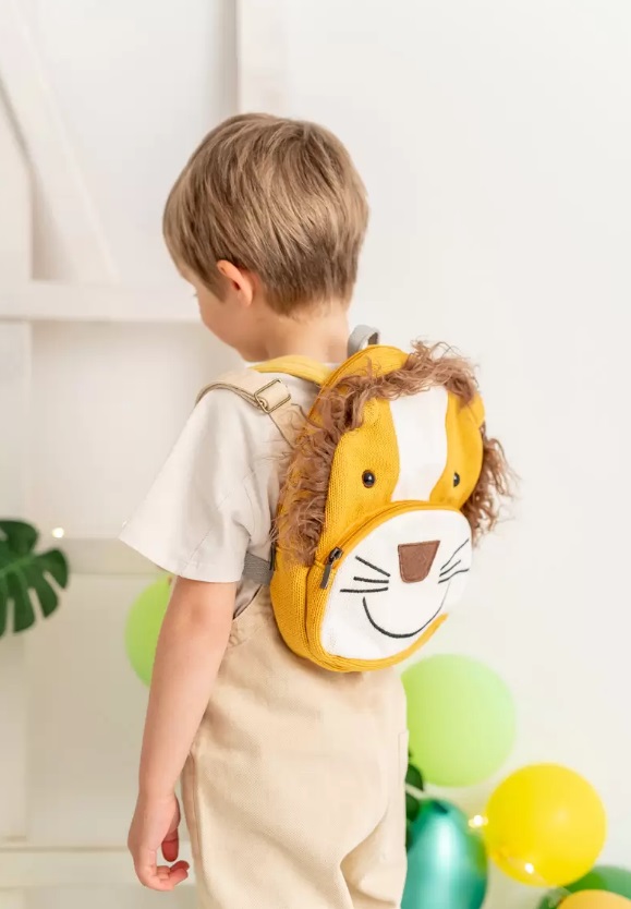 Mochila Simba Criança com mochila de leão amarela e bege em ambiente com balões