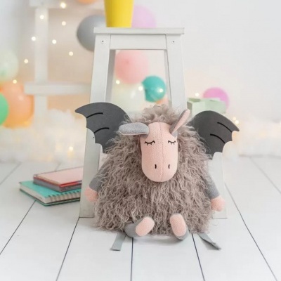 Mochila de unicórnio peluda com asas pretas à frente de banquinho branco e balões